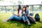 Group of Asian college student using tablet and laptop on grass field at outdoors. Technology and Education learning concept.