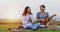 A group of Asian friends playing Ukelele and spending time making a picnic in the summer holidays.They are happy and have fun on