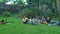 a group of Asian teenagers having tea with their friends in a green park