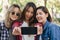 Group of Asian women using smartphone taking selfie while traveling at park in urban city in Bangkok, Thailand. Lifestyle