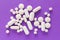 Group of assorted white tablets. Violet background.
