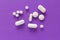 Group of assorted white tablets. Violet background.