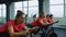 Group athletic girls performing aerobic riding training exercises on cycling stationary bike in gym