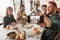 Group of attractive international friends sitting at the table with food spending time together. Young colleagues