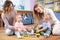 Group of babies toddlers playing with colorful educational toys and mothers in nursery room