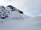 A group of backcountry skiers hiking along a steep north face and high alpine peak on their way to the top on a ski tour in the Al