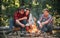 Group of backpackers relaxing near campfire. Friends spend leisure weekend forest nature background. Tourists relaxing