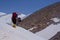 Group of backpackers with trekking poles passing the snow-covered slope