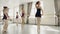 Group of ballet dancers are rehearsing dance with their teacher practising movements and walking on tiptoes. Slim girls