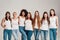 Group of beautiful diverse young women wearing white shirt and denim jeans looking at camera while posing together