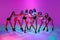 Group of beautiful women dance high heel dance, training over pink studio background in neon light