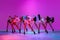 Group of beautiful women dance high heel dance, training over pink studio background in neon light