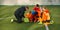 Group of boys, children training football with professional coach on field outdoors. Man showing sportive tactics and