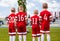 Group of boys football soccer players standing together on green