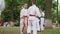 Group boys and girls in kimono participate karate and single fight outdoors, martial arts training in park, sport for