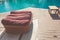 Group of brown towel setting on wooden basket beside swimming pool.