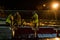 A group of builders repairs a bridge across the river at night under the light of lanterns in difficult winter conditions. Road