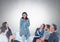 Group of business people sitting in circle meeting in front of blank grey background