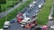 A group of cars and buses drive slowly past two fire trucks on a fire hose. Traffic jam