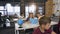 Group of Caucasian pupils of elementary school learning independently in the class while male korean teacher somesing