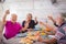 Group of cheerful old senior people at home during lunch take selfie picture and clink with white wine to celebrate and enjoy