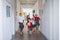 A group of cheerful small school kids in corridor, running and jumping.