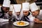 Group of chefs looking at prepared pasta in kitchen