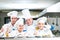 A group of chefs posing with delicious meal in high luxury restaurant.