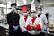 Group chefs standing together in the kitchen at restaurant wearing protective medical mask and gloves in coronavirus new normal