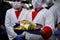 Group chefs standing together in the kitchen at restaurant wearing protective medical mask and gloves in coronavirus new normal