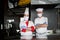 Group chefs standing together in the kitchen at restaurant wearing protective medical mask and gloves in coronavirus new normal