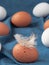 Group chicken eggs on blue fabric background. Ð¡hiken feather lies on an egg. Close-up