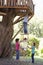 Group Of Children Climbing Rope Ladder To Treehouse