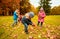 Group of children collecting leaves in autumn park