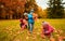 Group of children collecting leaves in autumn park