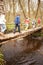 Group Of Children Crossing Stream On Wooden Bridge