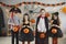 Group of children in different spooky Halloween costumes holding pumpkin baskets
