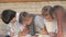 Group of children drawing sitting on a bench.