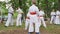 Group children in kimono participate karate outdoors, trainer spend martial arts training into park, sport for kids in