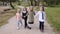 Group of children little girls holding hands and running happy along a pedestrian path in a city park in spring