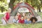 Group Of Children With Mother Having Fun In Tent In Countryside