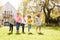 Group Of Children Running Across Garden Lawn At Home Looking Into Camera