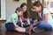 Group Of Children Sit On Porch Playing With Digital Tablet