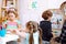 Group of children studying with help of teacher in bright classroom. Little boy standing near white magnetic board.