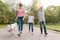 Group of children walking with a white husky dog, park road background.