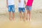 Group of children wearing casaual denim shorts having fun standing on sand at beach. Three toddler friends playing at