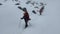 A group of climbers with large backpacks walk in a bundle along a snow-covered mountain trail.