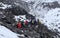 Group of climbers walk over rocks and stone ruins in the mountainous terrain