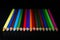 GROUP OF COLORED PENCILS ALIGNED ON BLACK BLACKGROUND