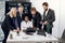 Group of confident high-skilled multiracial businesspeople, standing at the table and discussing business strategy